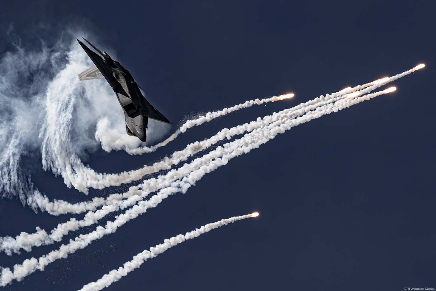 F-22 Raptor in a blue sky with flares